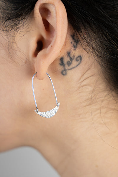 A close up image of a Crescent Moon Earring with a lace imprint worn on the body