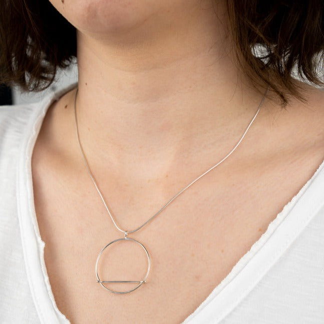 A close up image of the Kinetic Pendant worn on the body