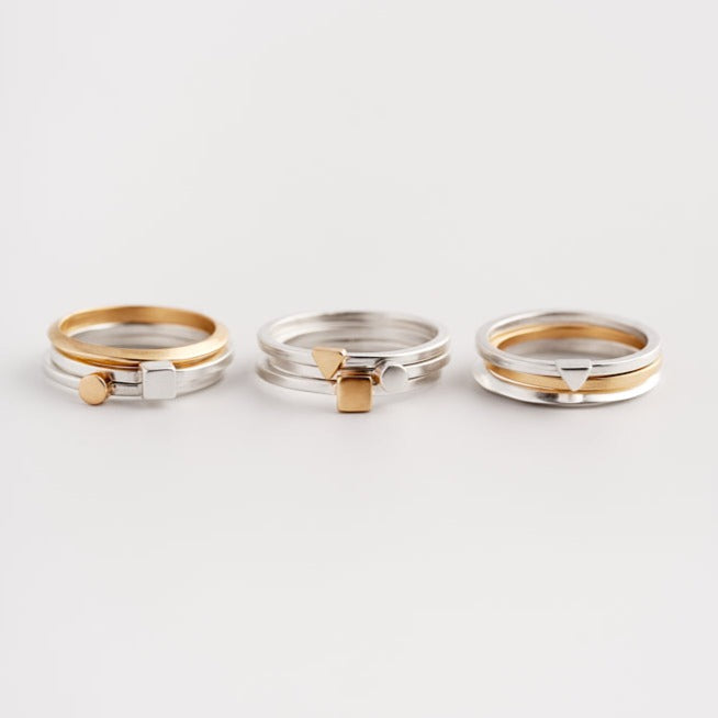An image of three stacks of Everyday Bands and Tiny Rings in silver and gold