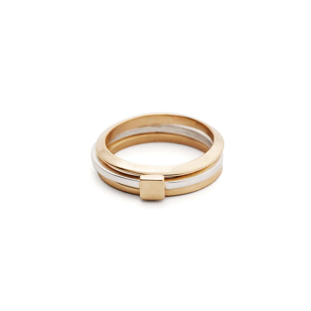 An image of the Tiny Ring, Square in silver and gold stacked with two Everyday Bands in gold